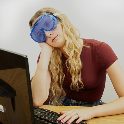 睡眠不足体験ゴーグルを着けて、机でうとうとしている人